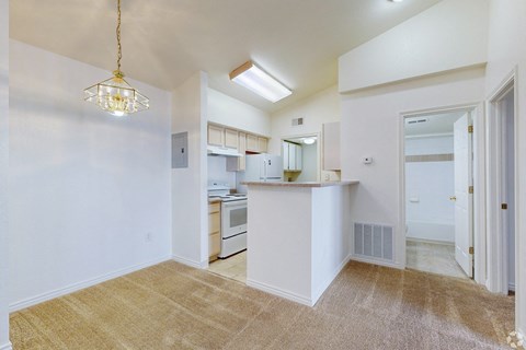 A kitchen area with a white counter and a hanging light fixture.