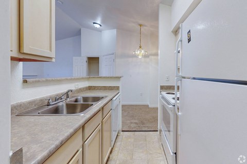 A kitchen with a white refrigerator, sink, and cabinets.
