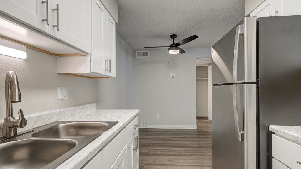 a kitchen with white cabinets and a stainless steel refrigerator and sink