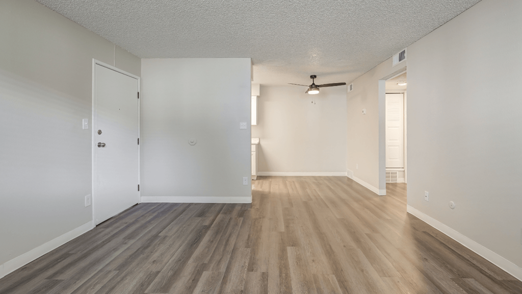 an empty living room with white walls and wood flooring