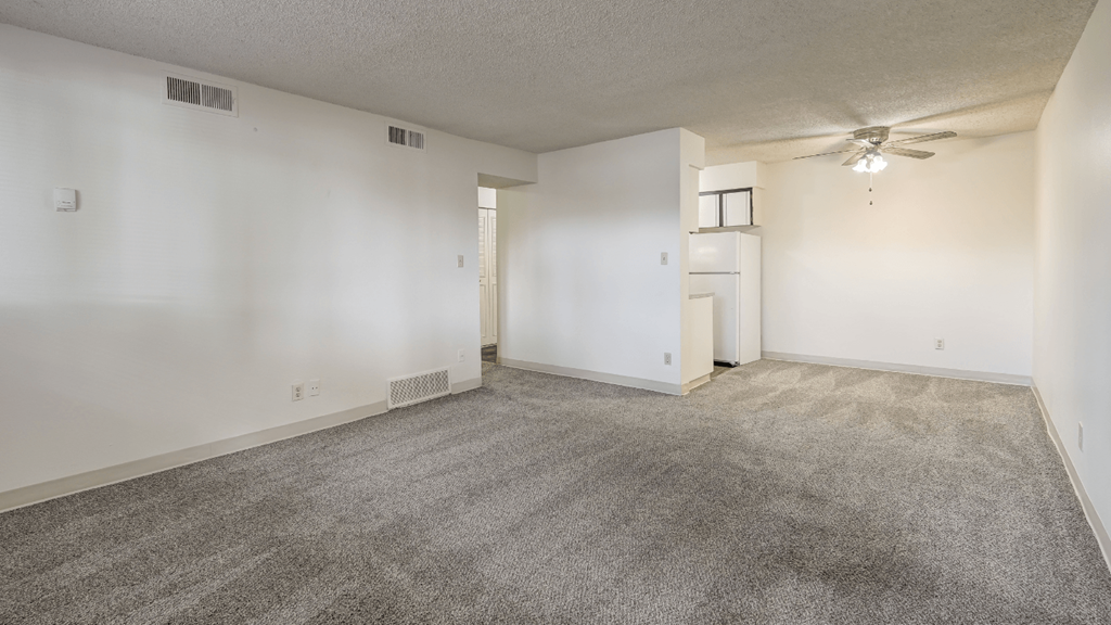 an empty living room with carpet and a ceiling fan