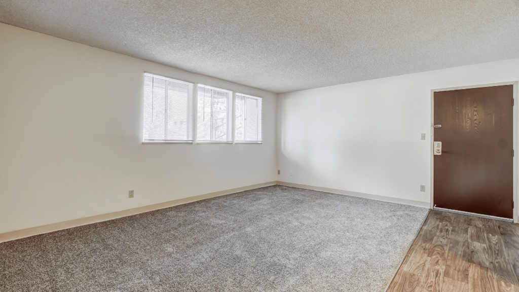 an empty living room with a door and window