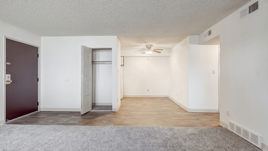 an empty living room with white walls and a ceiling fan