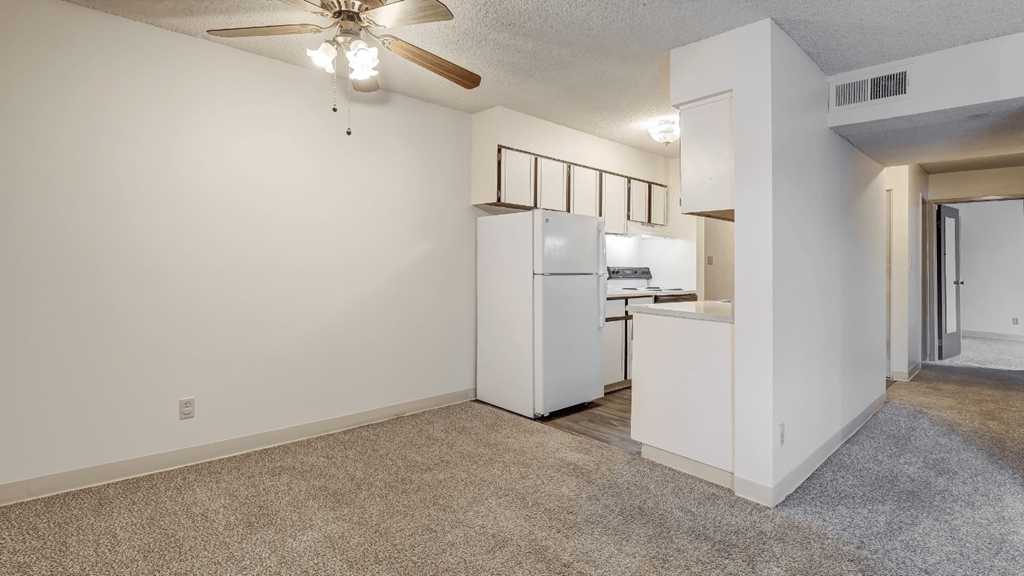 the spacious living room and kitchen with white appliances and a ceiling fan