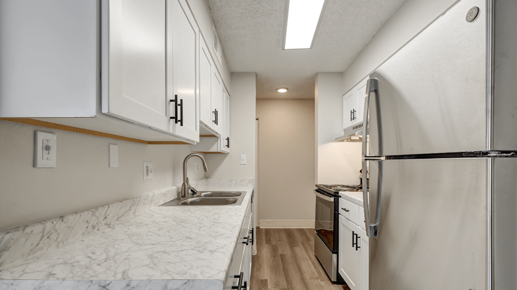a kitchen with white cabinets and a sink and a refrigerator