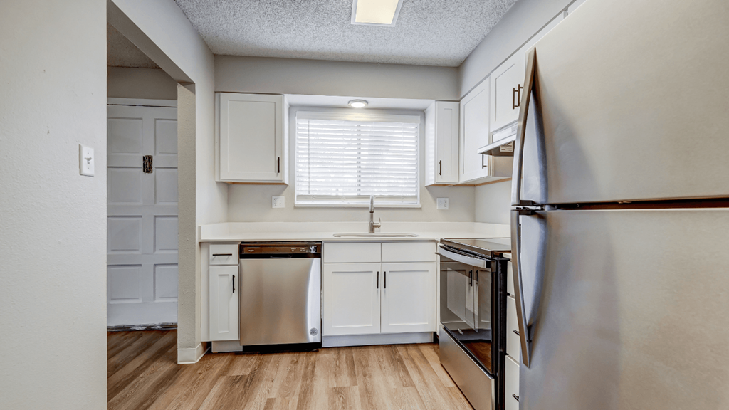 an empty kitchen with white cabinets and stainless steel appliances