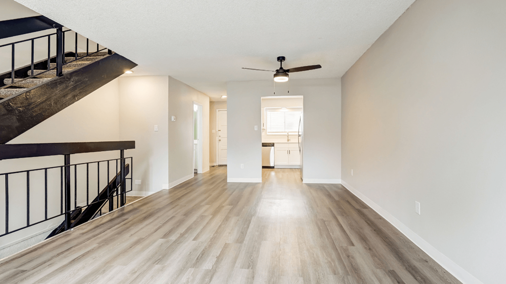 an empty living room with wood floors and a ceiling fan