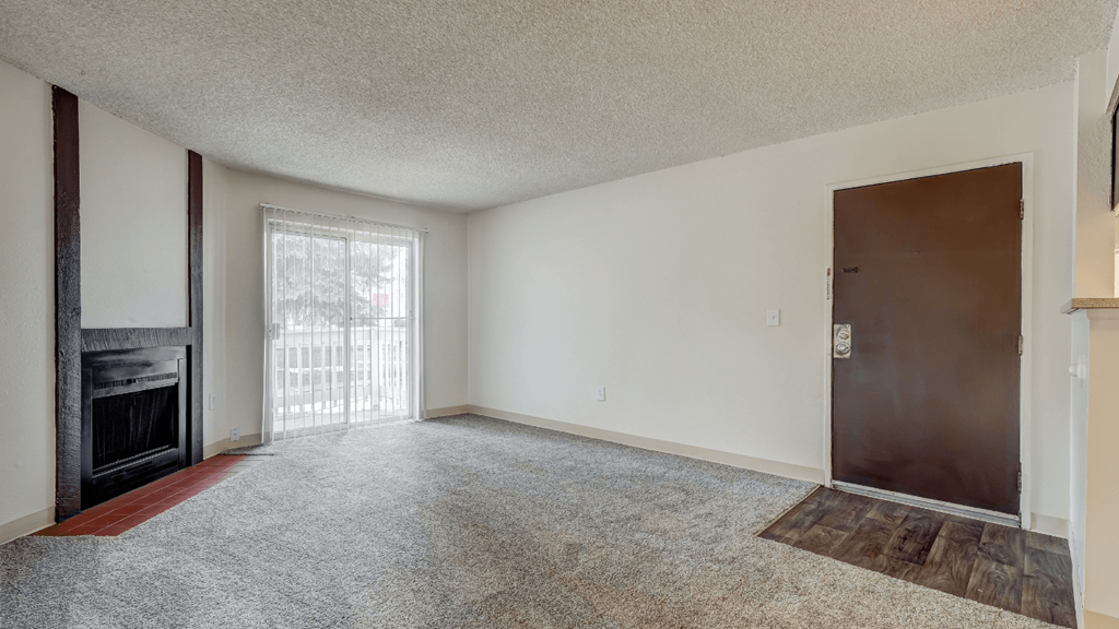 an empty living room with a fireplace and a sliding glass door