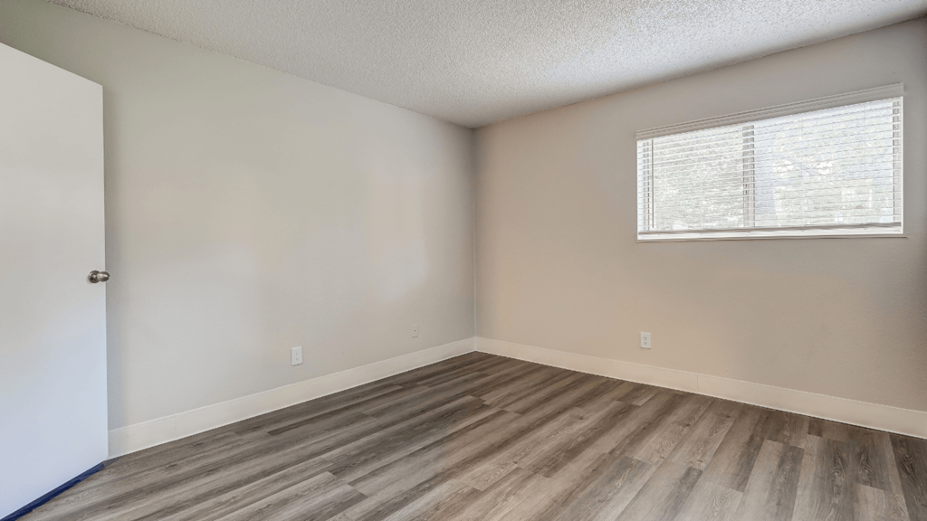 an empty room with wooden floors and a window