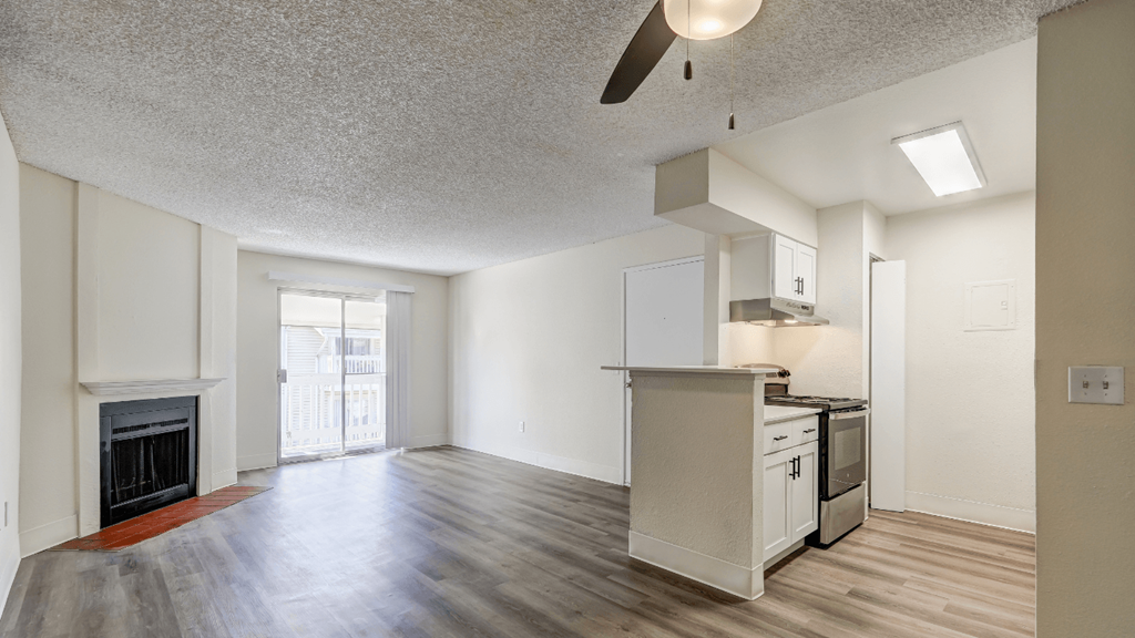 an empty living room with a fireplace and a kitchen