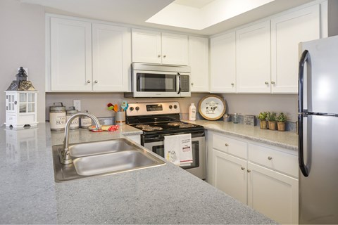 A kitchen with white cabinets and a black refrigerator.