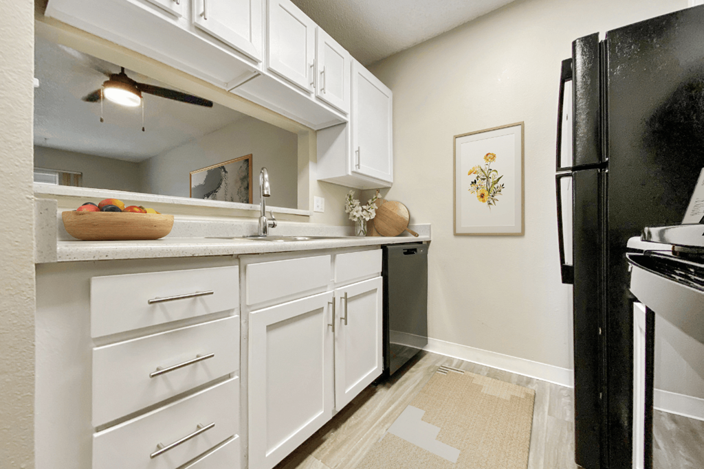 a kitchen with white cabinets and a black refrigerator