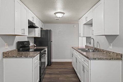 A kitchen with white cabinets and a granite countertop.