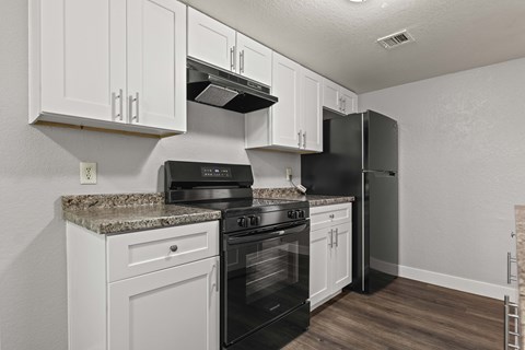 A kitchen with black appliances and white cabinets.