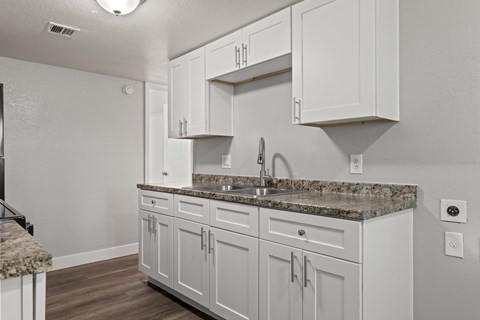 A kitchen with white cabinets and a granite countertop.