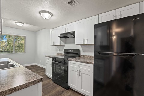 A kitchen with black appliances and white cabinets.