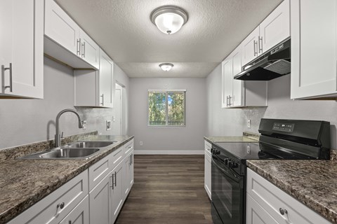 A kitchen with granite countertops and white cabinets.