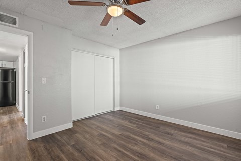 A room with a ceiling fan and wood flooring.