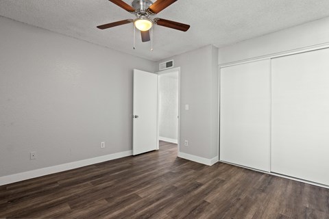 A room with a ceiling fan and wood flooring.