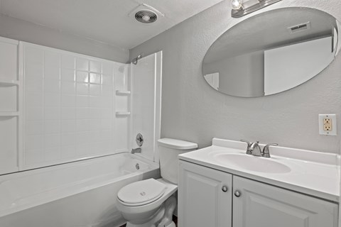 A white bathroom with a toilet, sink, and bathtub.