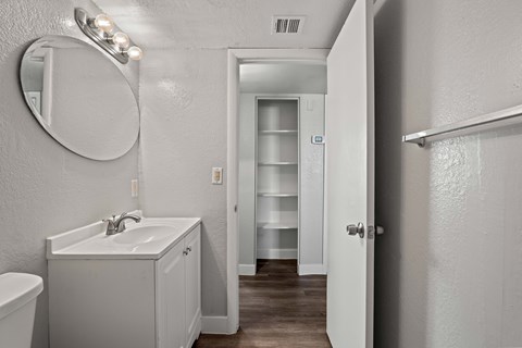 A white bathroom with a sink, mirror, and toilet.