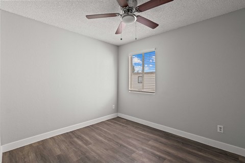 A room with a ceiling fan and a window with blinds.