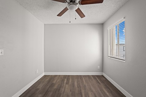 A room with a ceiling fan and a window with blinds.