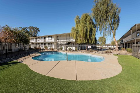 A swimming pool in a grassy area with a building in the background.