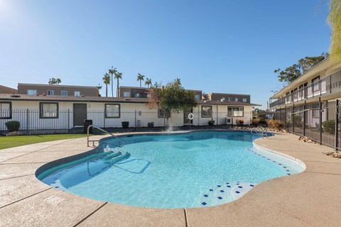 A swimming pool surrounded by a concrete floor and a fence.