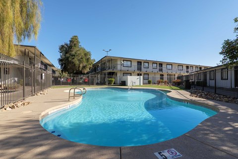 A swimming pool surrounded by a fence and buildings.