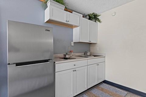 A kitchen with a stainless steel refrigerator and white cabinets.