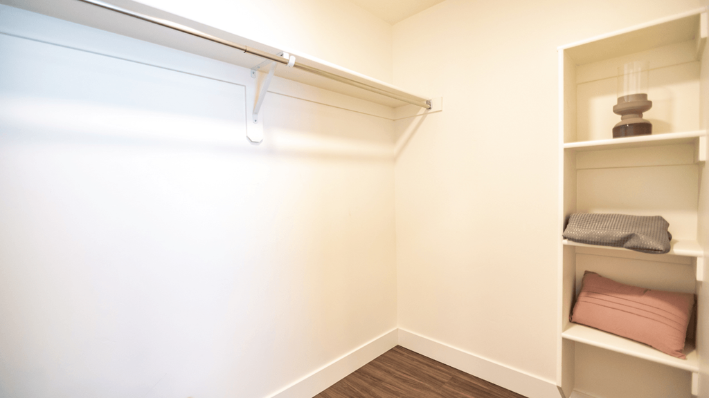 a walk in closet in a small room with shelves and a white wall