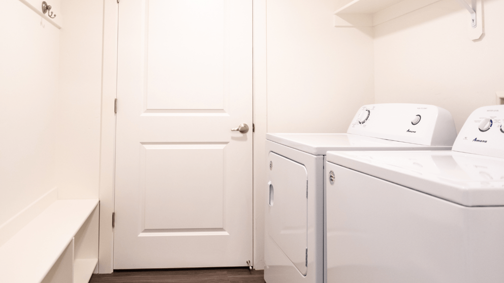 a laundry room with a washer and dryer and a white door