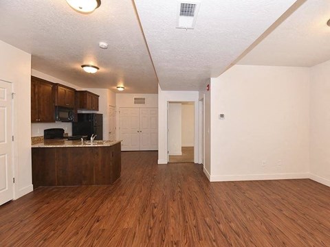 an empty living room and kitchen with wood floors