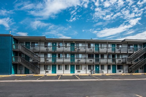 A large apartment complex with a parking lot in front.