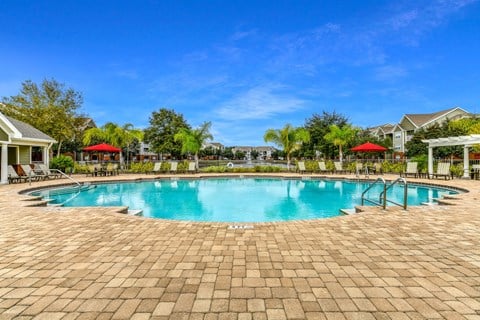 A large outdoor swimming pool surrounded by a brick patio.