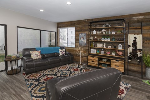 A living room with a black leather couch and a wooden bookshelf.