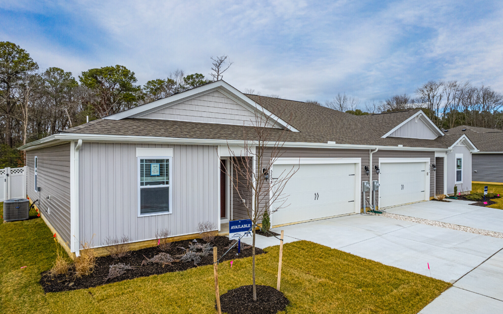 the front of a white house with a driveway and garage doors