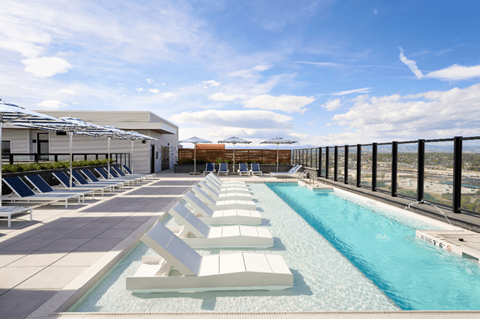 A pool with sun loungers and a building in the background.
