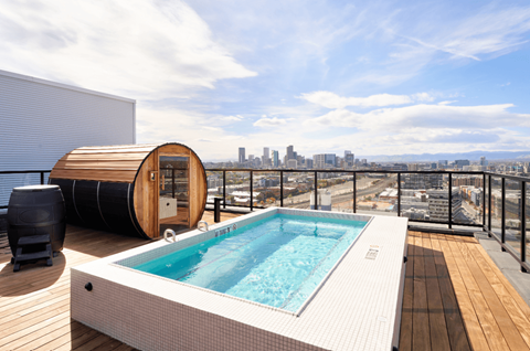 A hot tub on a wooden deck with a city skyline in the background.