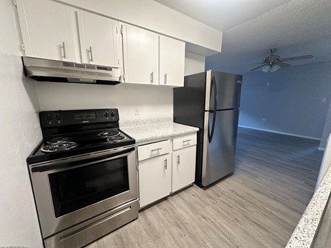 A kitchen with a stove, refrigerator, and cabinets.