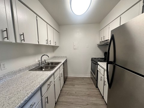 A kitchen with a stainless steel refrigerator and a granite countertop.