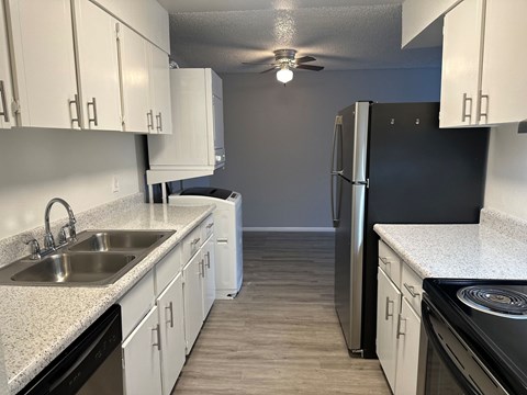 A kitchen with white cabinets and black appliances.