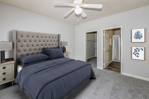 A bedroom with a large bed and a ceiling fan.