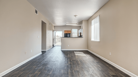 the living room and kitchen of an empty apartment with wood flooring