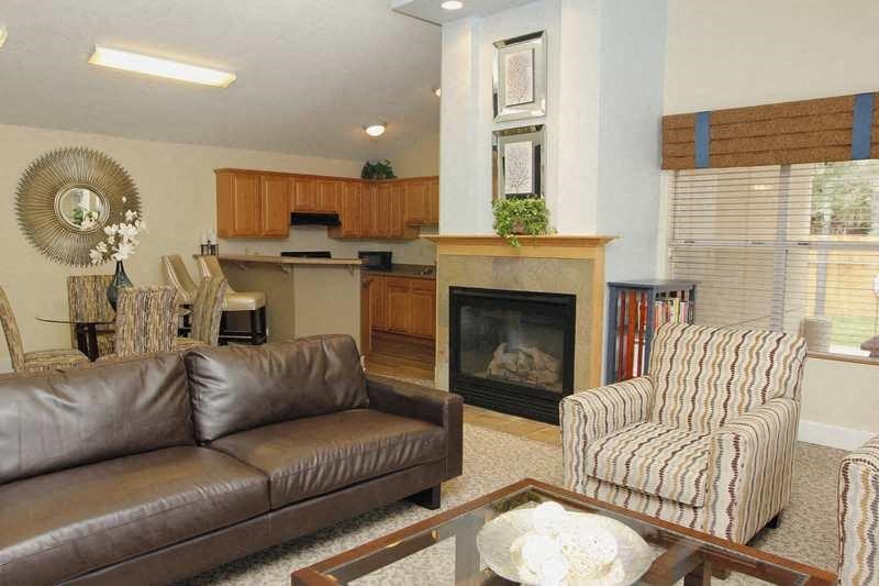A living room with a brown leather couch, a striped armchair, and a fireplace.
