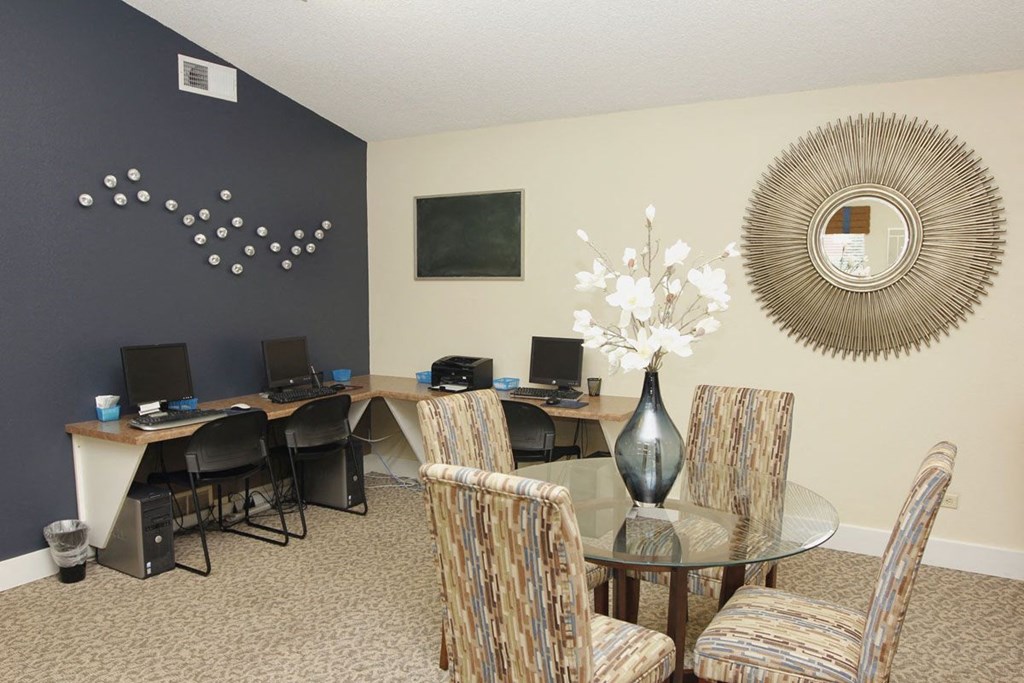 A room with a desk, chairs, and a mirror on the wall.