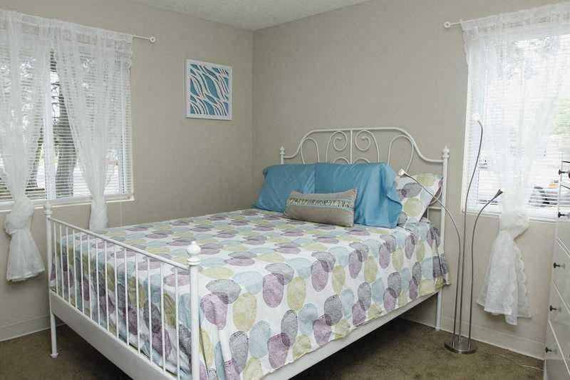 A white metal bed with a blue pillow and a floral patterned bedspread.