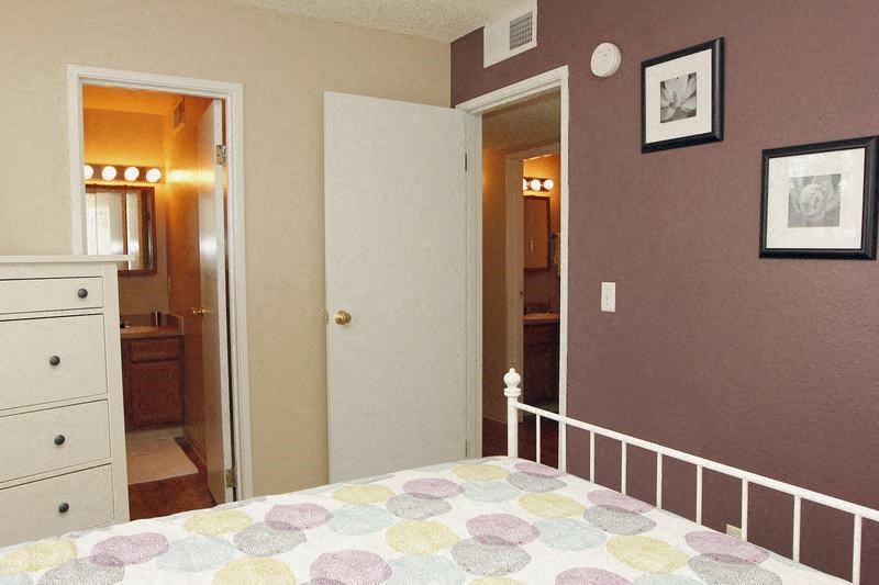 A bedroom with a bed, dresser, and two doors.