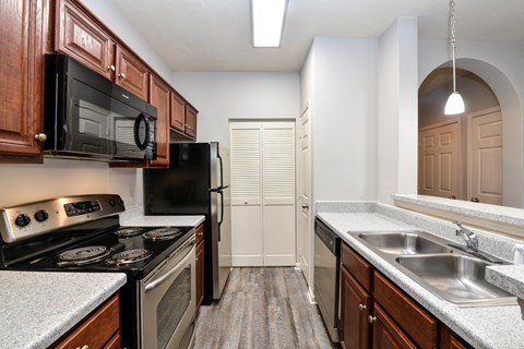 A kitchen with dark wood cabinets and a black refrigerator.